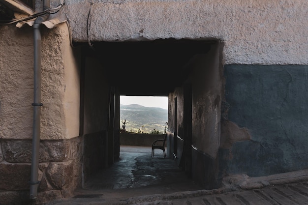 Allée d'architecture espagnole traditionnelle donnant sur un paysage de montagne et une chaise Pittoresque