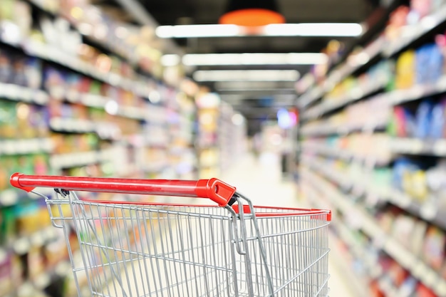 Allée de supermarché fond flou avec panier rouge vide