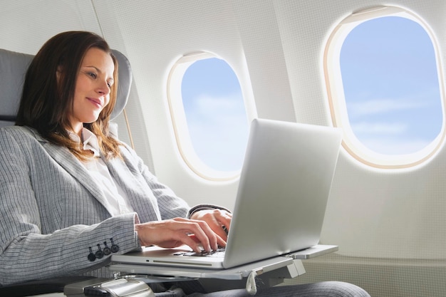 Allemagne Bavière Munich Mid adult businesswoman using laptop en cabine d'avion de classe affaires