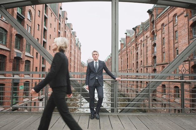 Allemagne Hambourg Businesswoman crossing bridge Businessman in background leaning against railing