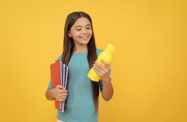 Aller boire un enfant joyeux avec du jus ou de l'eau et des livres étudiant adolescent souriant