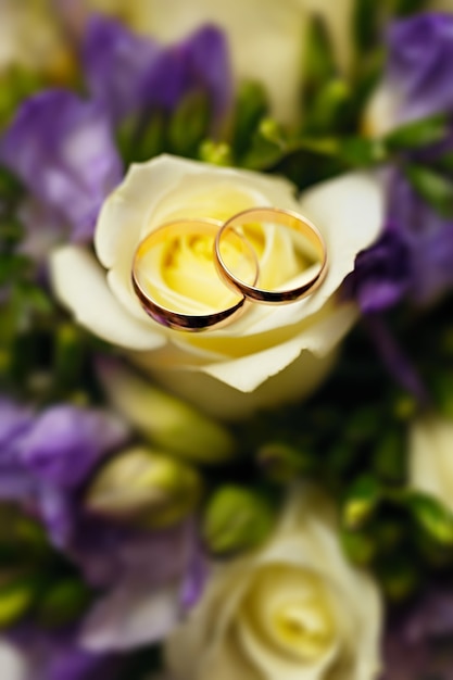 Alliances en or sur un bouquet de fleurs pour la mariée