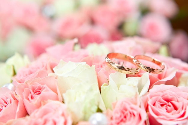 Alliances en or du marié et de la mariée sur un bouquet de fleurs.