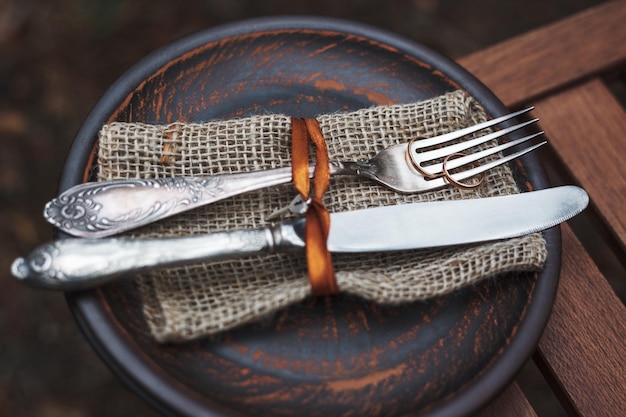 les alliances reposent sur une assiette d'argile avec une fourchette et un couteau sur la table