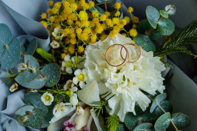 alliances se trouvent et beau bouquet comme accessoires de mariée. Deux anneaux d'or et fleurs de mariage.