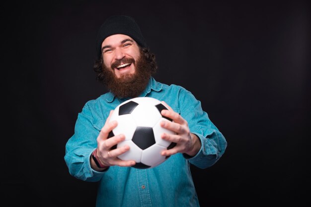 Allons jouer au football. Heureux homme barbu tenant un ballon de football et à la recherche