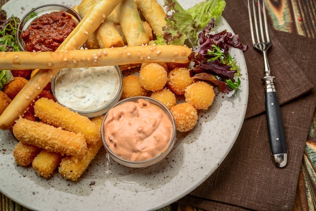 Allsorts de snacks frits avec deux sauces différentes sur fond noir