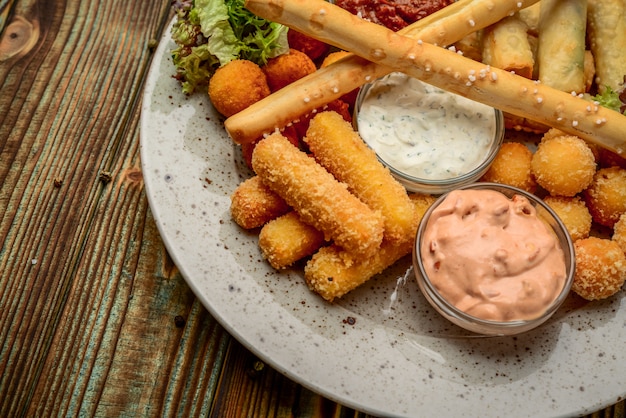 Allsorts de snacks frits avec deux sauces différentes sur fond noir