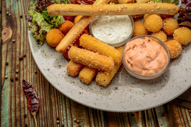 Allsorts de snacks frits avec deux sauces différentes sur fond noir