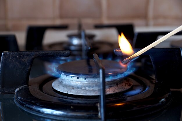 Photo allumage par une allumette d'un anneau de gaz sur la cuisinière