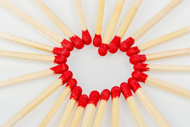 Allumette avec une tête en forme de coeur rouge sur fond blanc