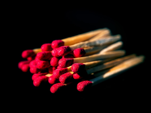 Allumettes en bois avec têtes de soufre rouge sur fond noir