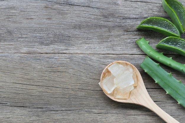 Aloe Vera fraîche tranchée dans une cuillère en bois sur un plancher en bois marron.