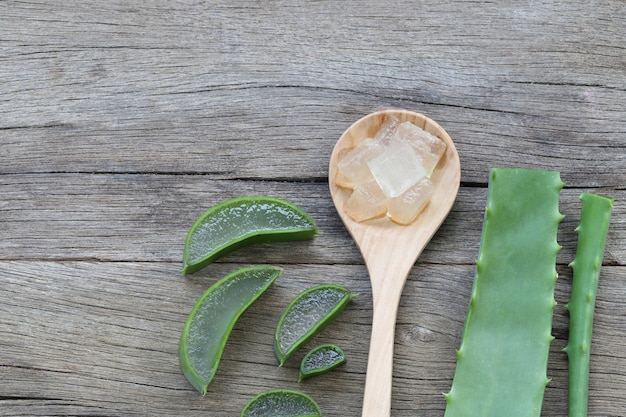 Aloe Vera fraîche tranchée dans une cuillère en bois sur un plancher en bois marron.