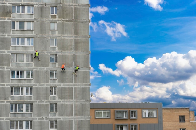 Alpinisme industriel travaillant en altitude Trois hommes examinent le mur d'un immeuble résidentiel