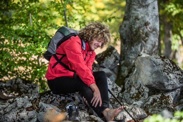 Un alpiniste assis sur un rocher tenant son alpiniste blessé à la cheville