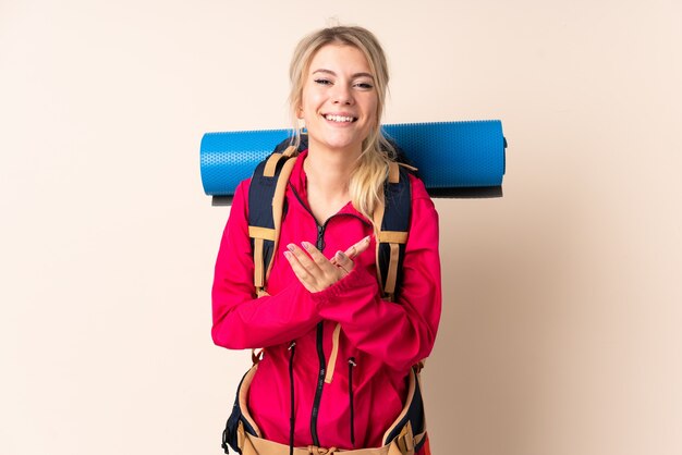 Alpiniste femme avec un gros sac à dos sur mur isolé applaudissant