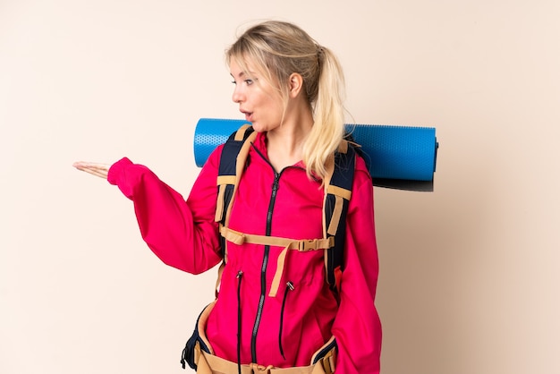 Alpiniste femme avec un gros sac à dos sur mur isolé