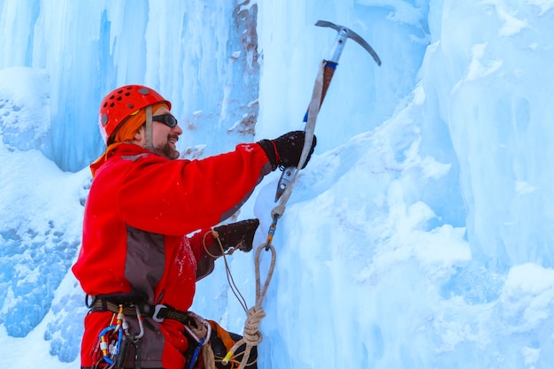 L'alpiniste avec piolet fait une ascension d'un mur de glace enneigé, portrait mi-long