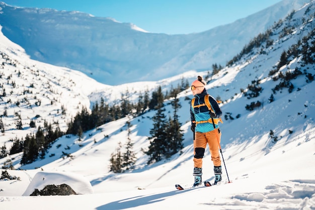 Alpiniste randonnée à ski dans l'arrière-pays ski alpiniste dans les montagnes Ski de randonnée dans un paysage alpin avec des arbres enneigés Sports d'hiver aventure