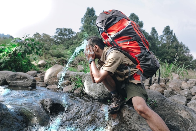 un alpiniste se lave le visage dans la rivière