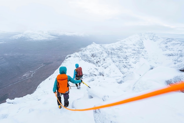 Les alpinistes escaladant une crête enneigée de Liathach en Ecosse