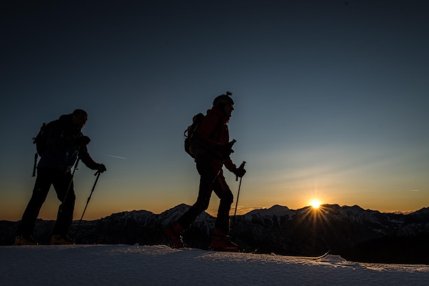 Les alpinistes escaladent les montagnes avec du ski le soir au soleil