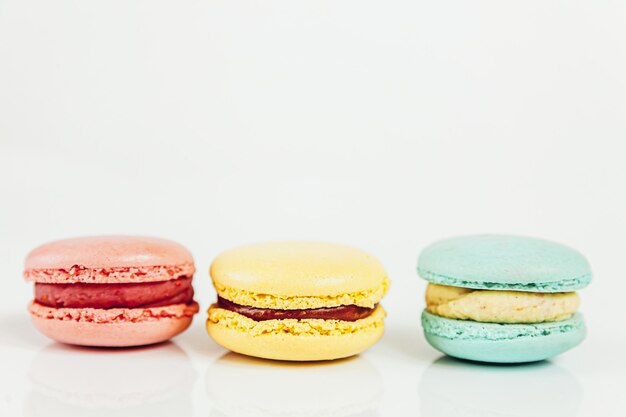 Amande douce rose pastel coloré bleu jaune macaron ou gâteau dessert macaron isolé sur blanc