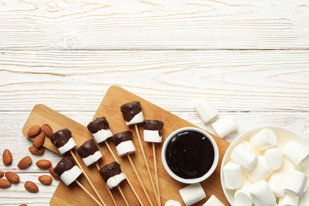 Amande et guimauve au chocolat sur fond de bois blanc, vue de dessus