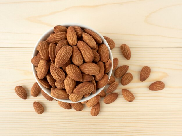 Amandes biologiques dans un bol en céramique et amandes tas vue de dessus sur bois