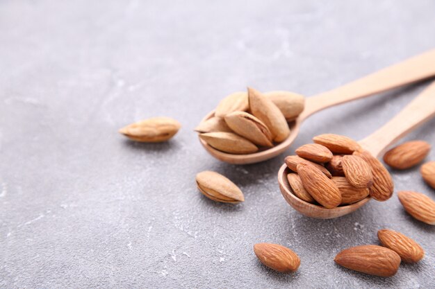 Amandes sur une cuillère en bois sur fond gris