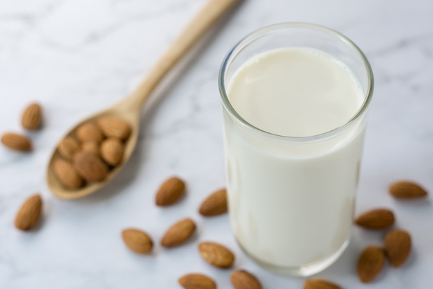 Amandes à la cuillère en bois et lait d'amande sur marbre blanc