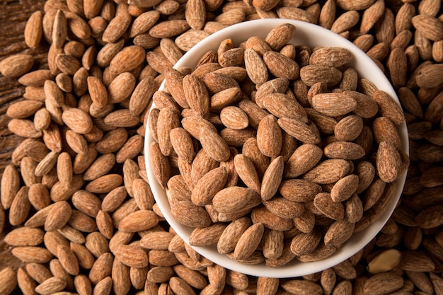 Amandes dans un bol blanc sur fond de bois