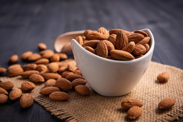 Amandes dans un bol blanc sur une table en bois foncé Concept d'amande avec copyspacetopview