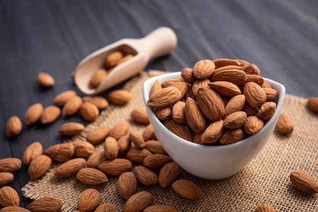 Amandes dans un bol blanc sur une table en bois foncé Concept d'amande avec copyspacetopview