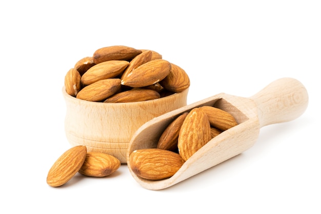 Amandes dans un bol en bois et cuillère sur une surface blanche, gros plan