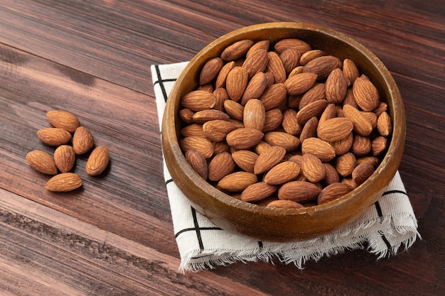 Amandes dans un bol en bois sur la table, collation saine, nourriture végétarienne.