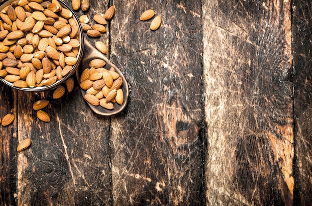 Amandes dans un bol et une cuillère en bois. Sur fond en bois.