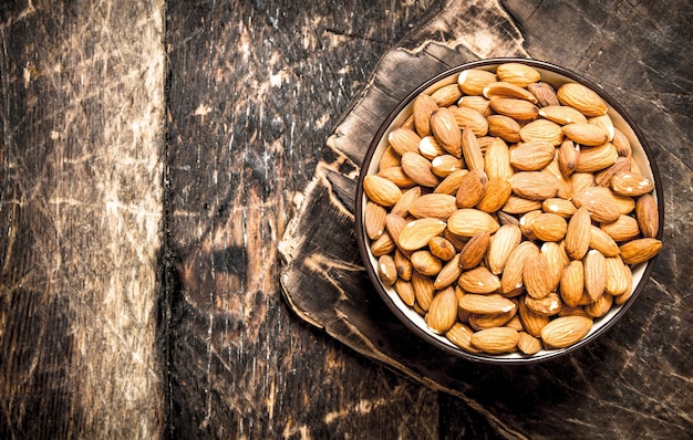 Amandes dans un bol. Sur fond en bois.