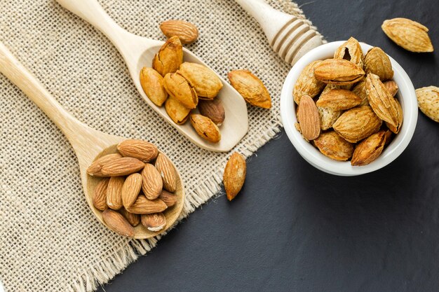 Amandes dans un bol noir sur un fond en bois rustique foncé