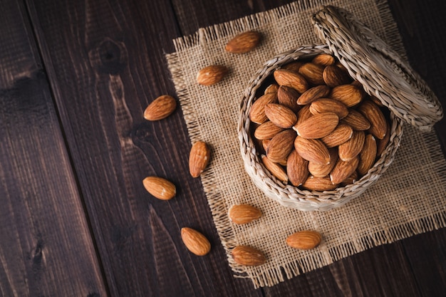 Amandes dans un panier en bois sur une table en bois sombre