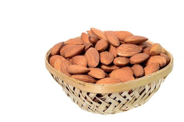 Amandes dans un panier en bois avec tas isolé sur fond blanc