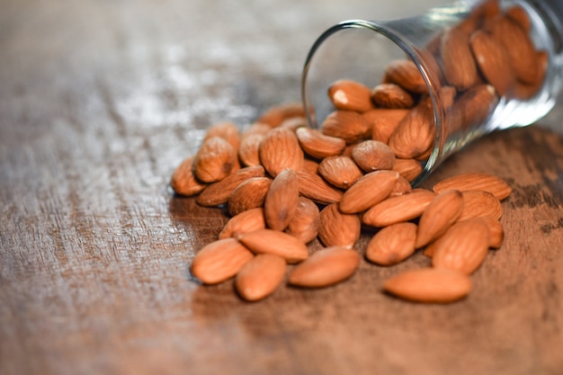 Amandes dans un verre sur fond de bois rustique foncé