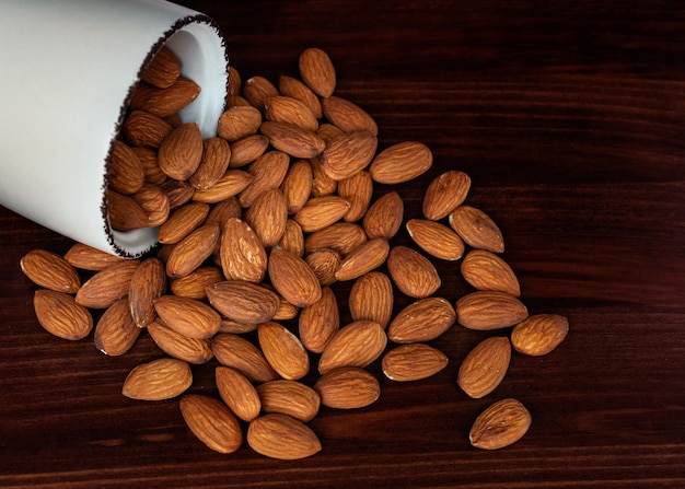 Amandes dispersées dans un bol en bois rustique foncé contre