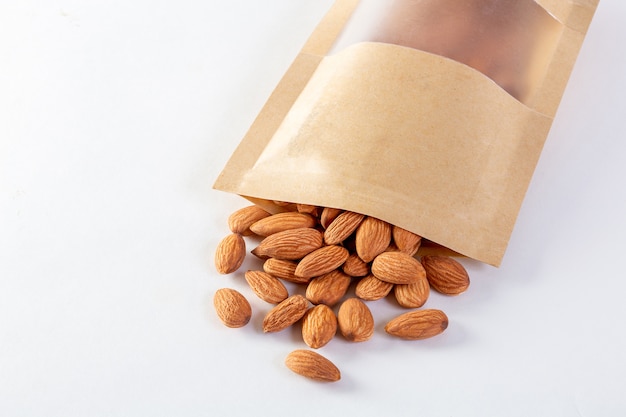 Amandes emballées dans des sacs en papier sur un fond blanc.