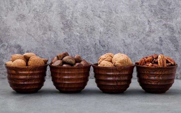 Photo amandes entières noix entières noisettes entières et noix de pécan dans un bol en bois avec fond en pierre profondeur de mise au point sélective de champ