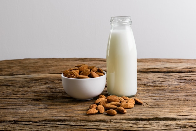 Amandes pelées avec bol et bouteille de lait d&#39;amande sur fond en bois rustique