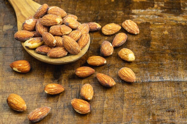 Les amandes sont versées sur la table avec une cuillère à bois.