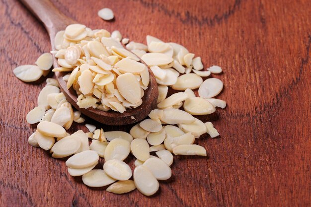 Photo amandes tranchées dans une cuillère en bois et un espace de copie de fond en bois