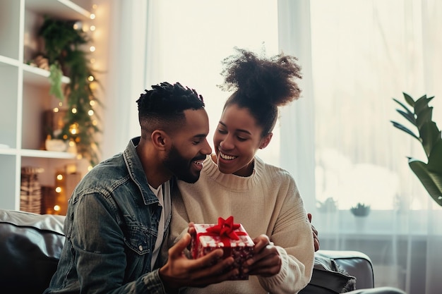 Amant africain américain homme présentant un cadeau à sa petite amie dans une chambre à la maison symbole de leur amour Ma